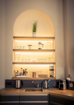 Een keuken met een houten aanrecht, een spoelbak en een plank met glazen en een plant.