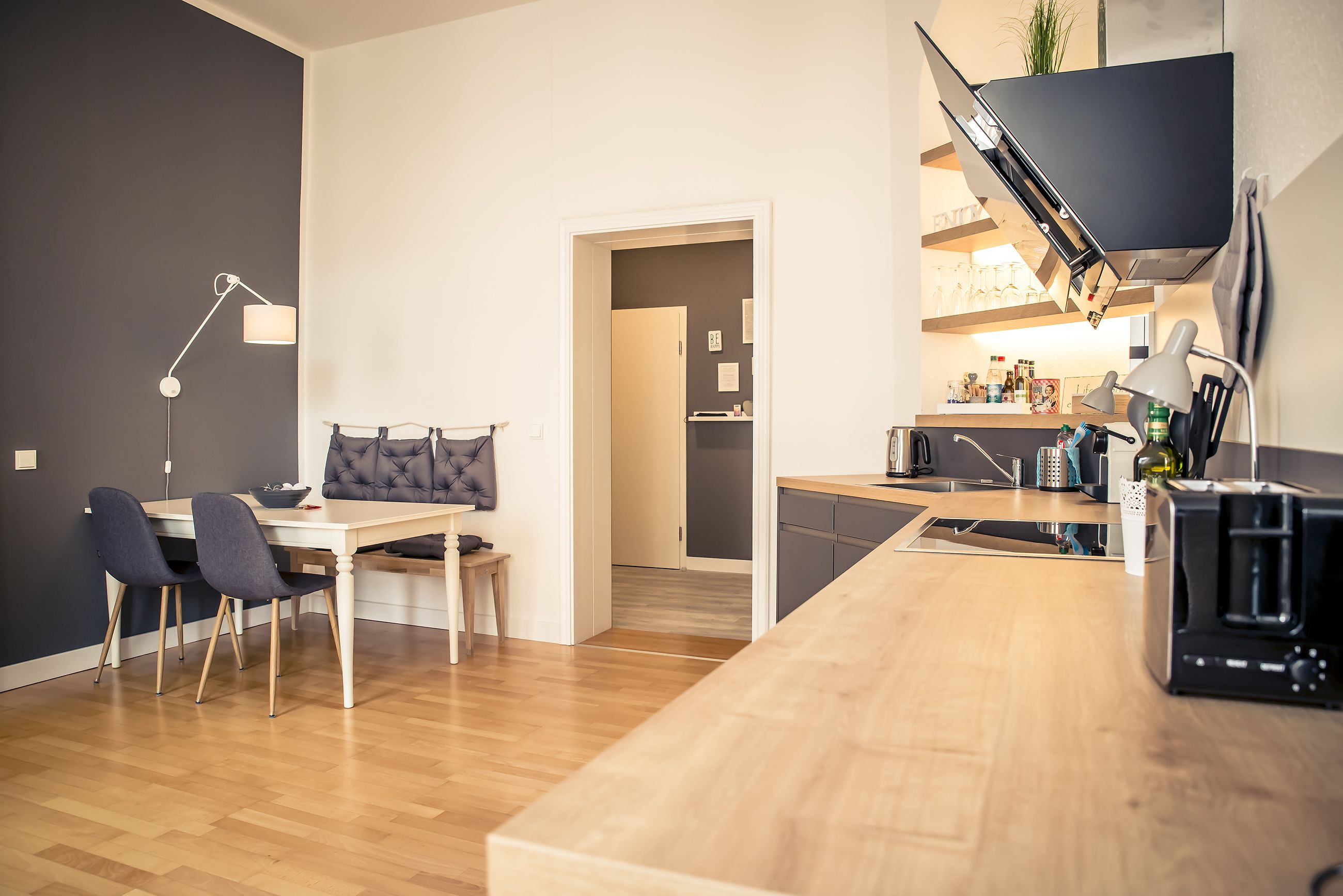 Una cocina moderna con encimera de madera, horno empotrado y microondas. Cuenta con un comedor con mesa y sillas.