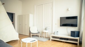 Een moderne woonkamer met een bank, een fauteuil, een televisie en een witte kast.