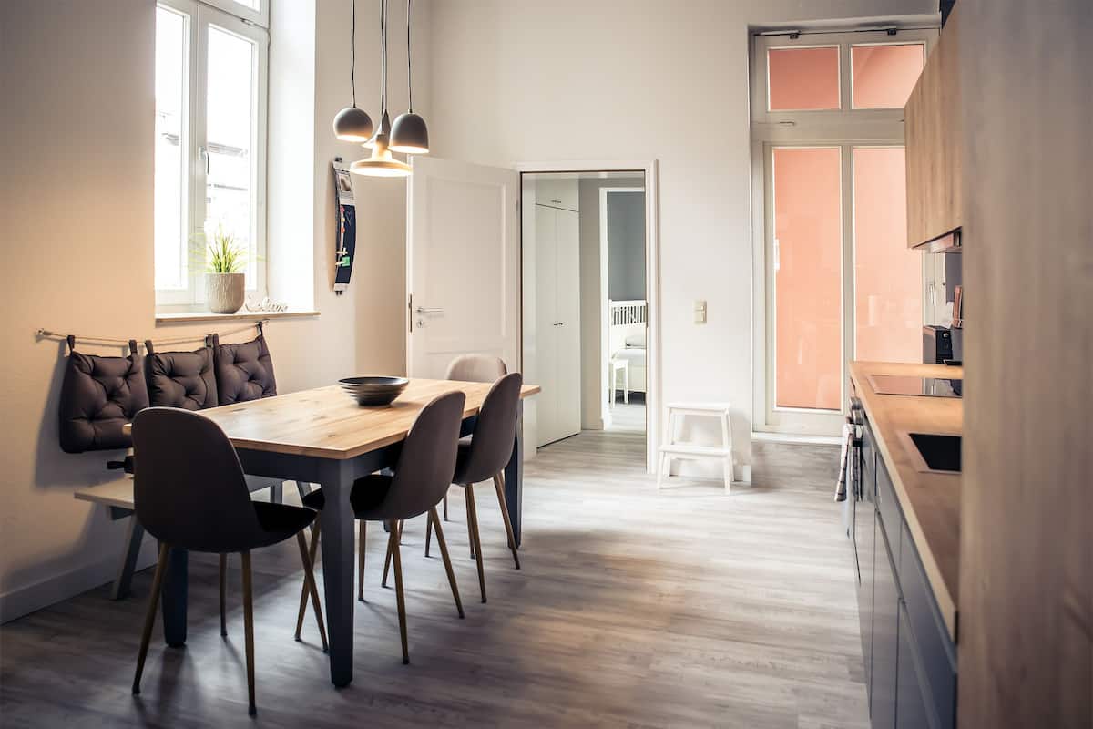 Eine moderne Küche mit Holzschränken und einem Essbereich mit Holztisch und -stühlen.