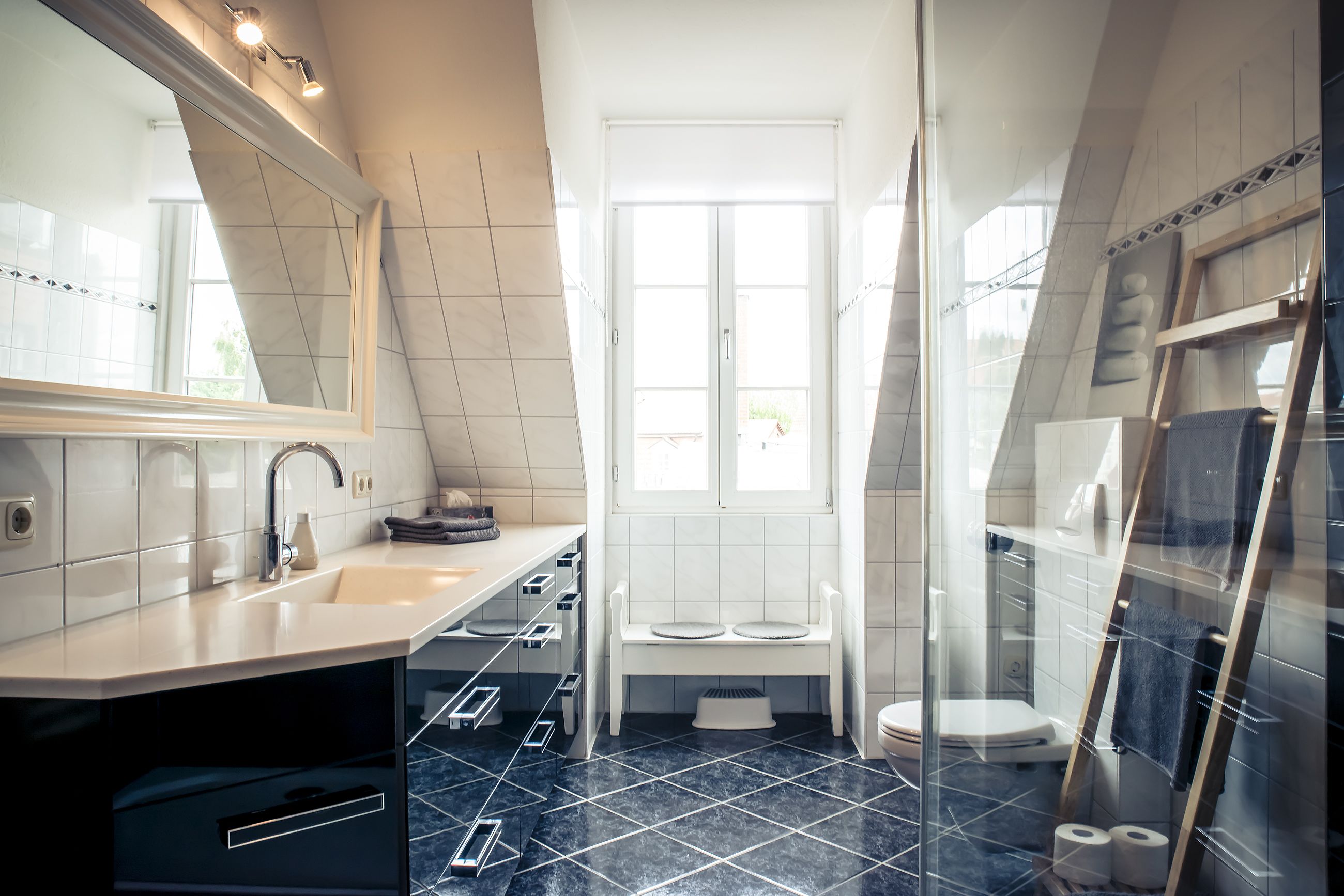 A modern bathroom with a large mirror, a sink, a toilet, and a shower area.