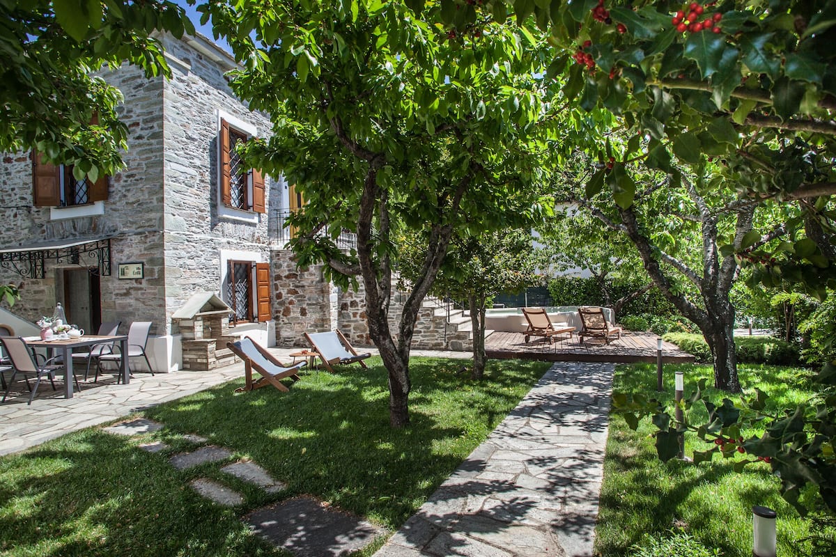 A stone building with a patio area, outdoor seating, and a garden.