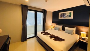 A hotel room with a large bed, two bedside tables with lamps, a window with curtains, and a painting on the wall. - The Seens Hotel (Krabi)