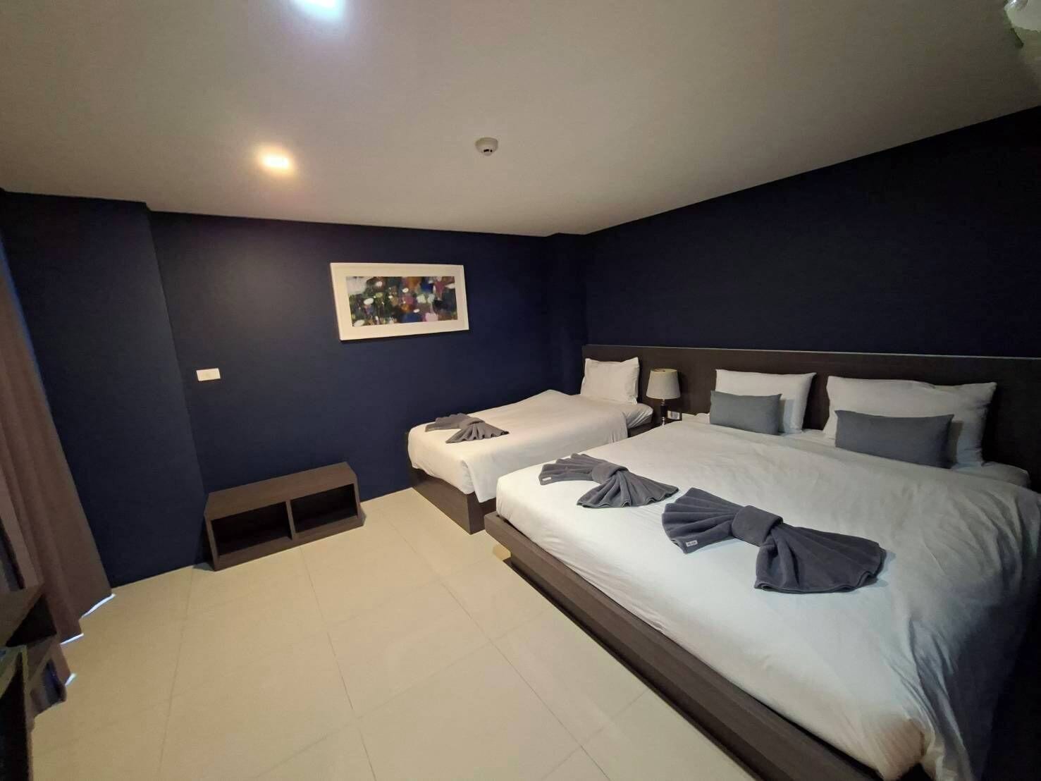 A hotel room with two beds, a small bedside table, a wall-mounted picture, and a ceiling light.