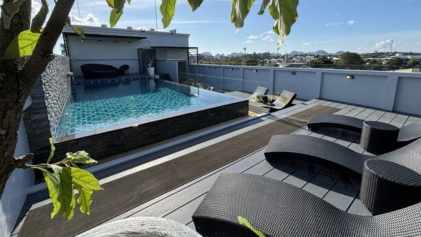 A rooftop pool area with a rectangular pool, lounge chairs, and a view of the cityscape. - The Seens Hotel (Krabi)