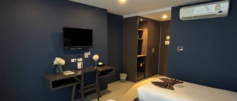 Habitación de hotel con dos camas, un escritorio, una silla, un televisor y un equipo de aire acondicionado.