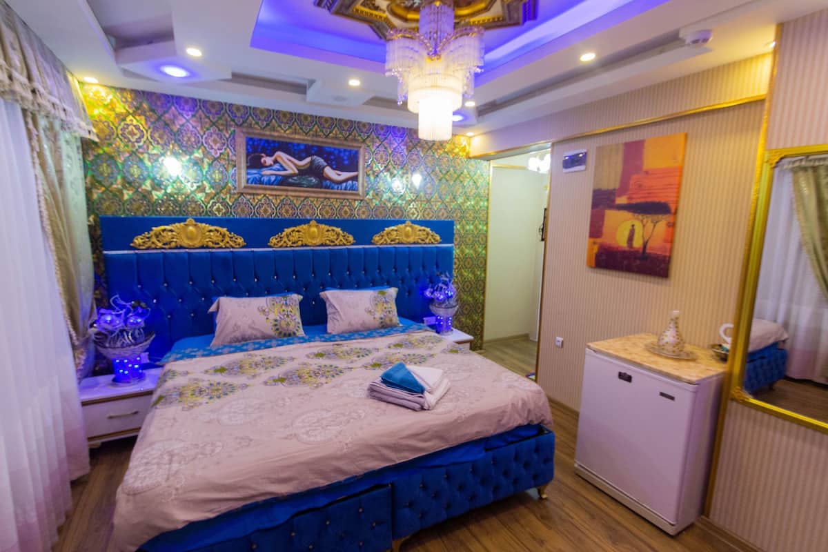 Un dormitorio con una cama grande, un aparador y un refrigerador pequeño.