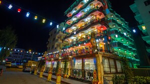 A multi-story building with balconies, string lights, and flags.