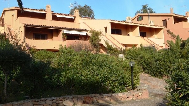 A building with multiple balconies, a stone pathway, and lush greenery. - AffittaSardegna - Trilo Bellavista 1 (Olbia)
