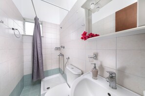 A modern bathroom with a shower, toilet, and sink. - Vergonis Studios (South Pelion)