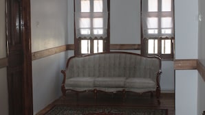 A room with a wooden floor, a patterned rug, a wooden bench, and a chandelier. - Huseyin Bey Konagi (Safranbolu)