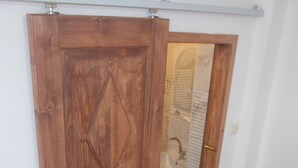 A bedroom with a wooden wardrobe, a bed with a beige quilt, and a towel on the bed. - Huseyin Bey Konagi (Safranbolu)