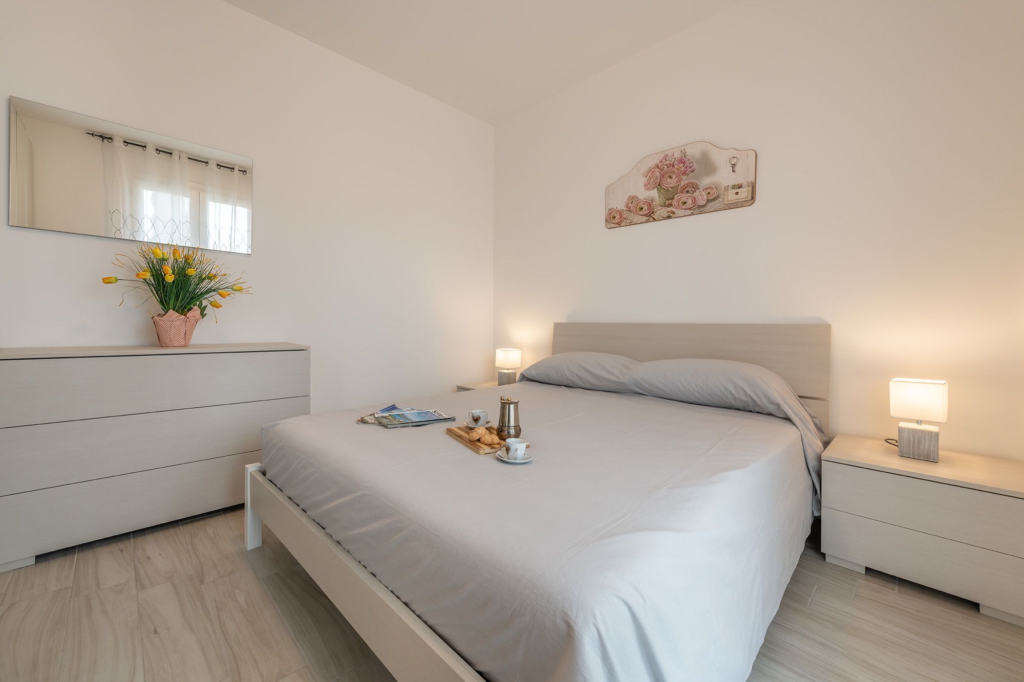 Un dormitorio moderno con cama, mesitas de noche, cómoda y espejo.
