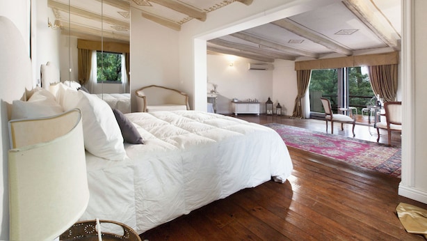 Un dormitorio amplio con una cama grande, un espejo y vistas al exterior.
