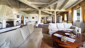 Un salón espacioso con chimenea, varias zonas de estar y un alto techo con intrincados trabajos de madera.