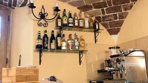 A bar area with shelves of liquor bottles, a coffee machine, and a wooden crate. - Donna Matilde (Pescocostanzo)