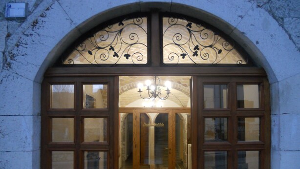 A hotel entrance with a large arched doorway, wooden doors, and a chandelier. - Donna Matilde (Pescocostanzo)