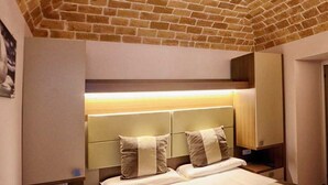 A hotel room with a brick ceiling, a bed with two pillows, a bedside table, and a nightstand. - Donna Matilde (Pescocostanzo)