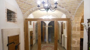 A wooden door with glass panels, a chandelier, and a stone wall. - Donna Matilde (Pescocostanzo)
