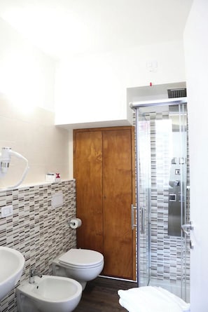 Un baño con puerta de madera, cabina de ducha y salpicadero azulejado.