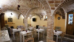 A dining area with brick arches, white tables, and chairs. - Donna Matilde (Pescocostanzo)