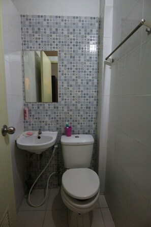 A bathroom with a toilet, sink, and a mirror. - Bann Bunga (Bangkok)