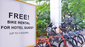 Letrero que ofrece alquiler gratuito de bicicletas para huéspedes del hotel, por hasta 3 horas, con una fila de bicicletas estacionadas cerca.