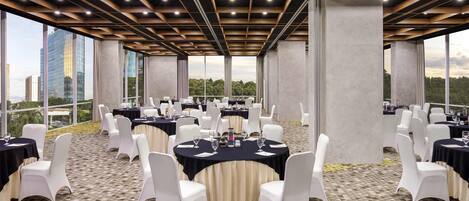Un salón de conferencias con mesas redondas, sillas blancas y un piso con diseño.