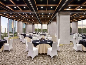 Un salón de conferencias con mesas redondas, sillas blancas y un piso con diseño.