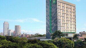 Un hotel alto de diseño moderno, con un llamativo logo verde en la fachada.