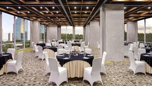 A conference room with round tables, white chairs, and a patterned floor. - ibis Styles Jakarta Simatupang (Jakarta)