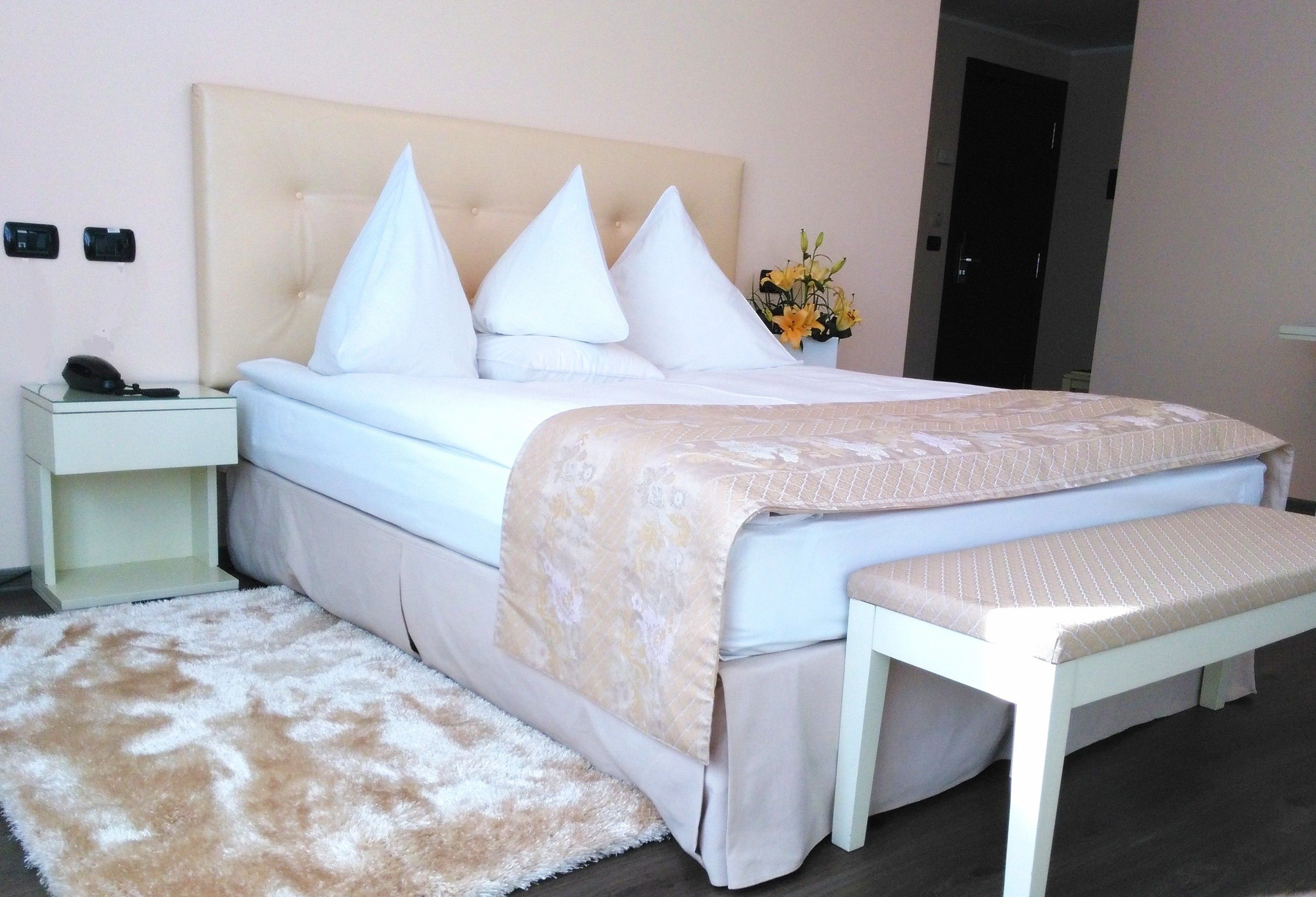 A neatly arranged bedroom with a bed, bedside tables, a bench, and a fluffy rug.