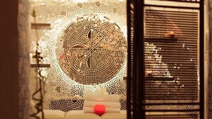 An interior view of a room with a large circular mosaic artwork on the wall, a bed with a red pillow, and a barred window. - Hotel Paradis Cluj Napoca (Cluj-Napoca)