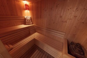 A wooden sauna with benches and a bench with a towel. - Hotel Paradis Cluj Napoca (Cluj-Napoca)