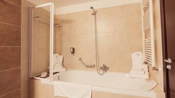 Un baño moderno con bañera, ducha y zona de ducha con mampara de vidrio.