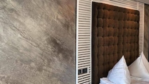 A modern bedroom with a tufted headboard, a bedside table with a phone, and a large bed with white bedding. - Hotel Paradis Cluj Napoca (Cluj-Napoca)