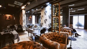 A restaurant interior with high-backed leather chairs, a wine rack, and a view of the city through large windows. - Hotel Paradis Cluj Napoca (Cluj-Napoca)
