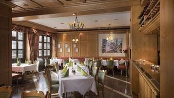 A restaurant with multiple tables, chairs, and a wine rack.