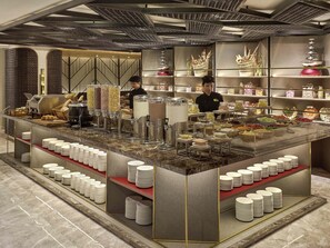 A buffet setup with various food containers, a coffee machine, and a staff member serving. - Novotel Jakarta Cikini Hotel (Jakarta)