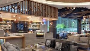 Un intérieur moderne avec un bar, des espaces pour s’asseoir et une vue sur la verdure.