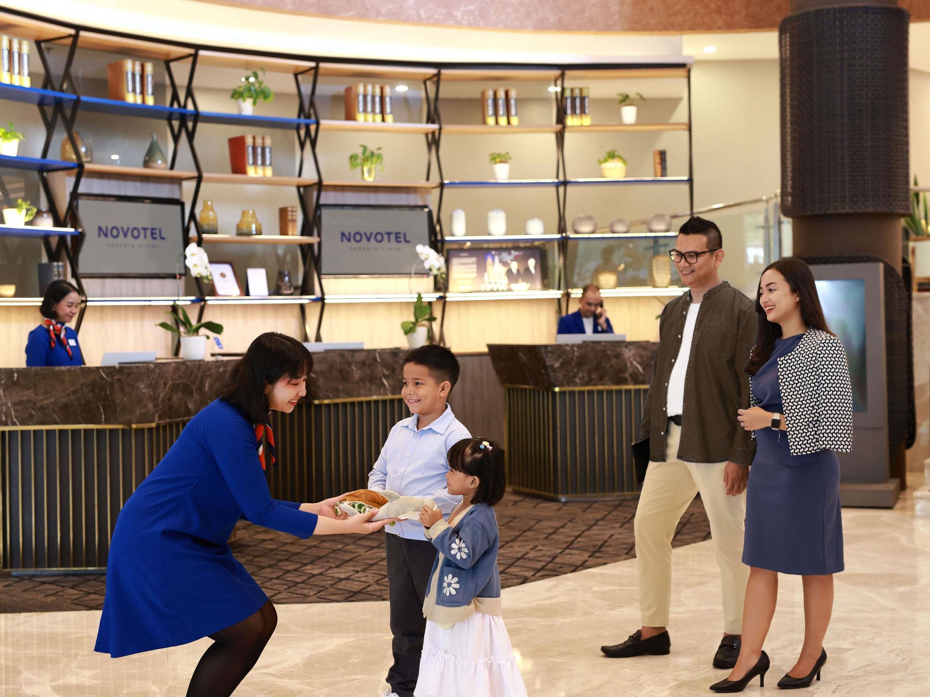Een hotel receptie met een balie, receptiemedewerker en een gezin.