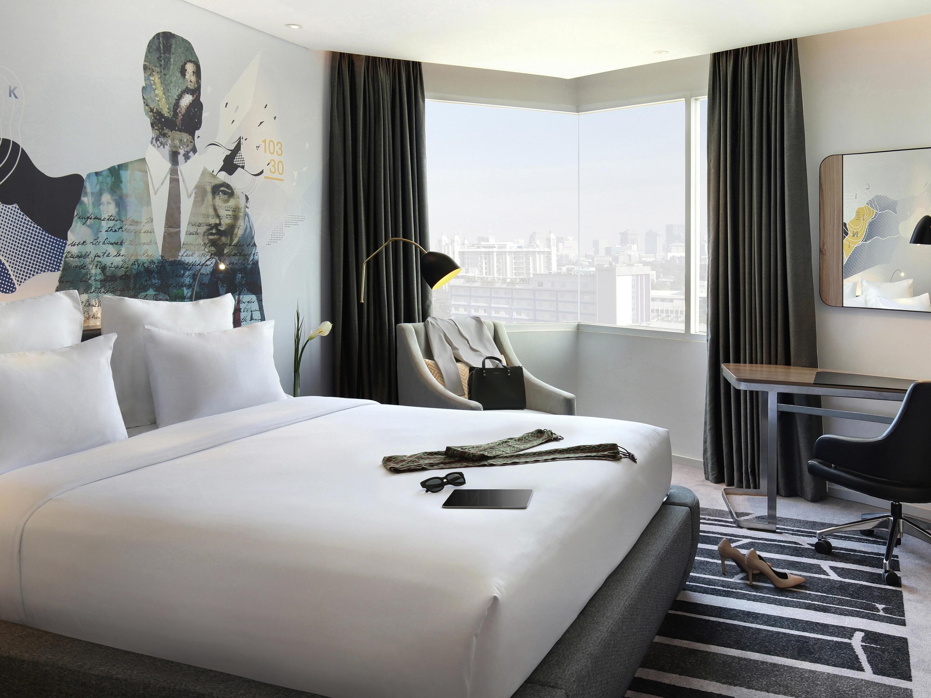 Une chambre d’hôtel avec un grand lit, un bureau, une chaise et une vue sur la ville.