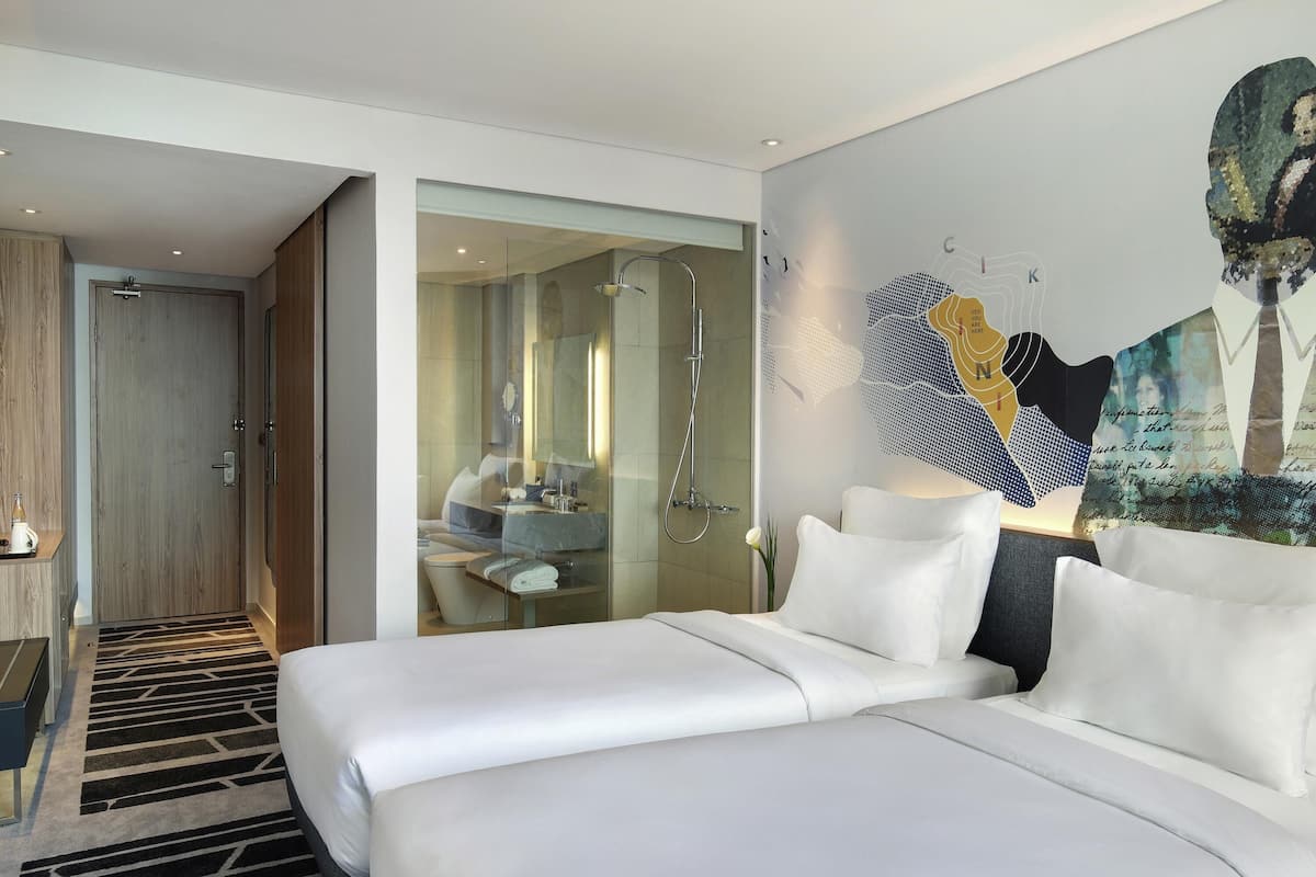 Ein Hotelzimmer mit Bett, Badezimmer mit Dusche und einer Glastrennwand.