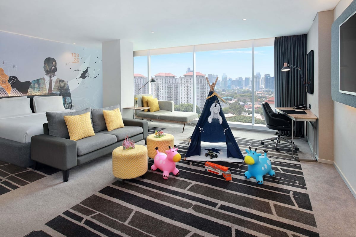 Un salon moderne avec un canapé, des poufs, une tente tipi et des jouets pour enfants.