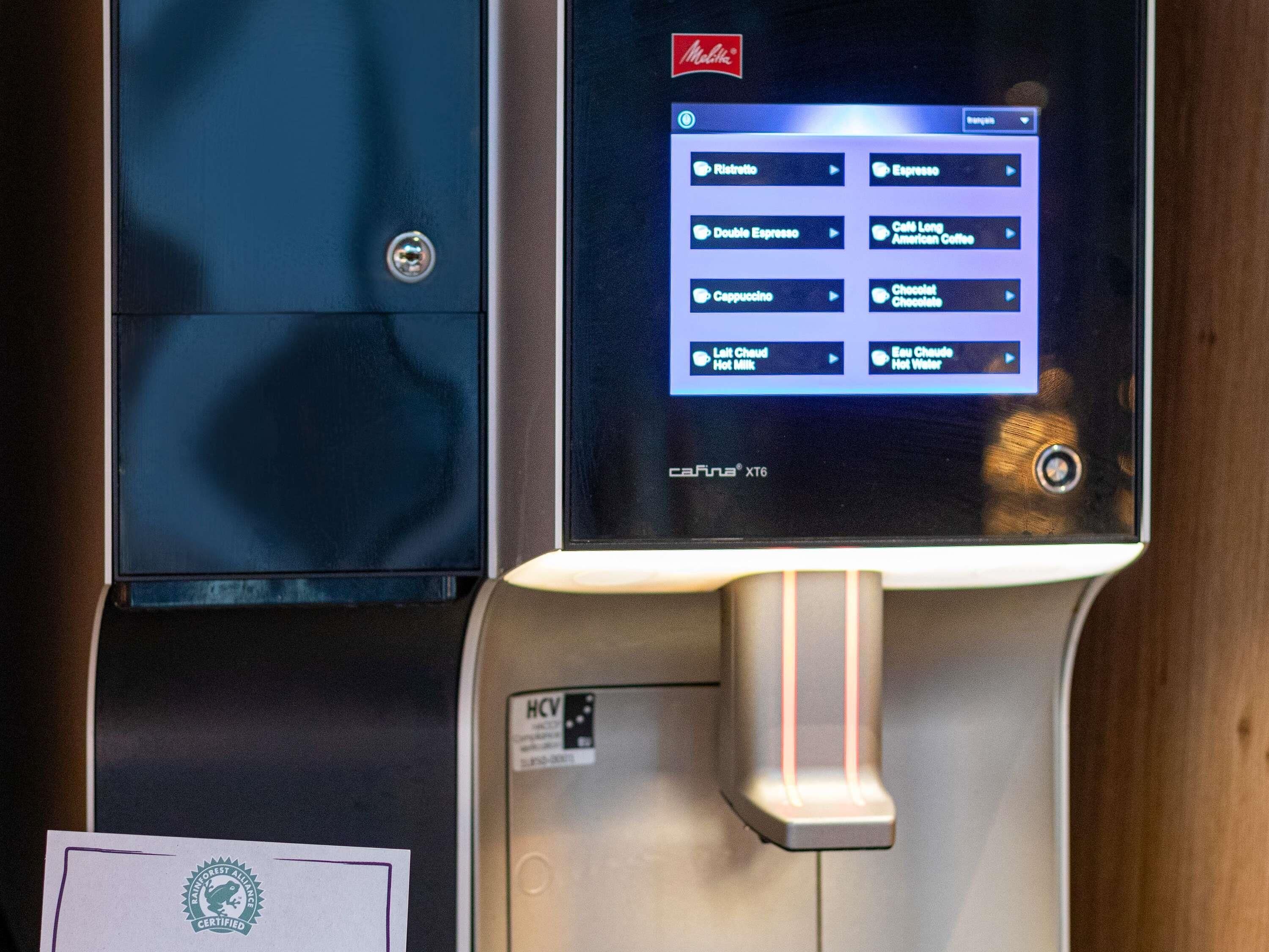 A coffee machine with a digital display menu, a water dispenser, and a certification label.