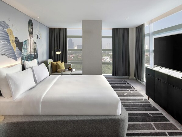 A modern hotel room with a large bed, a desk, and a city view. - Novotel Jakarta Cikini Hotel (Jakarta)