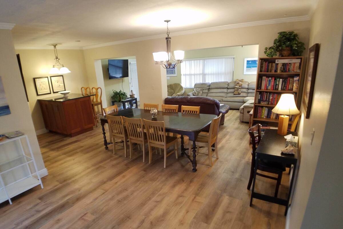 A spacious living area with a dining table, chairs, a sofa, and a bookshelf.