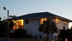 A two-story house with a balcony and a lit entrance. - The Sand Castle (Satellite Beach)