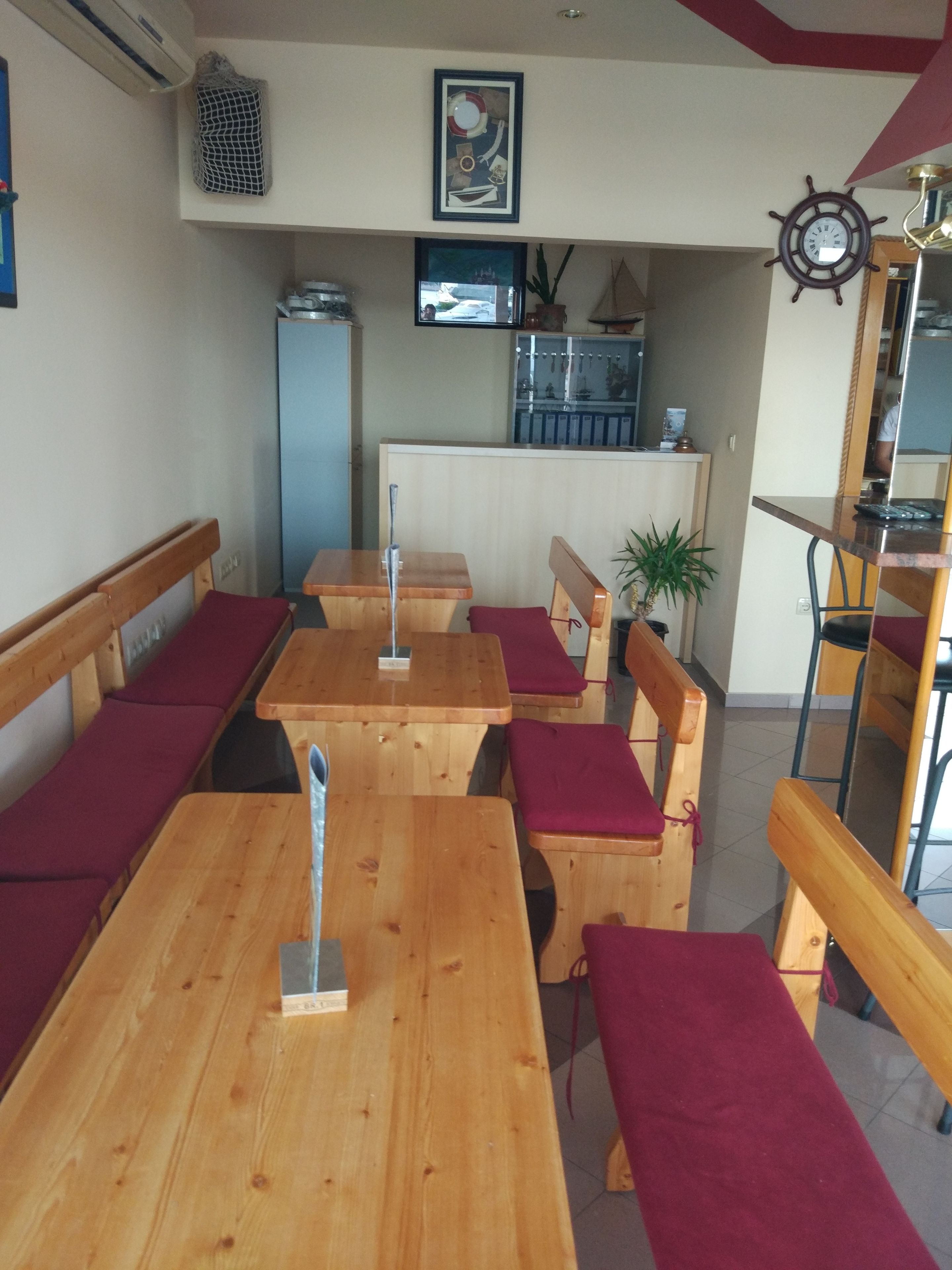 A restaurant with wooden tables and benches, a clock on the wall, and a plant in the corner.