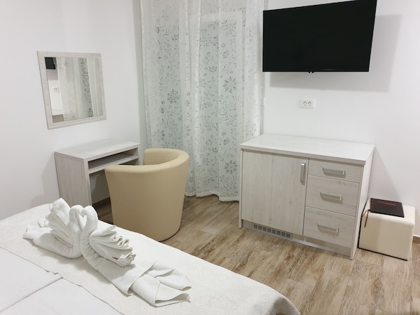 Ett hotellrum med en säng, ett skrivbord, en stol, en tv och en garderob.